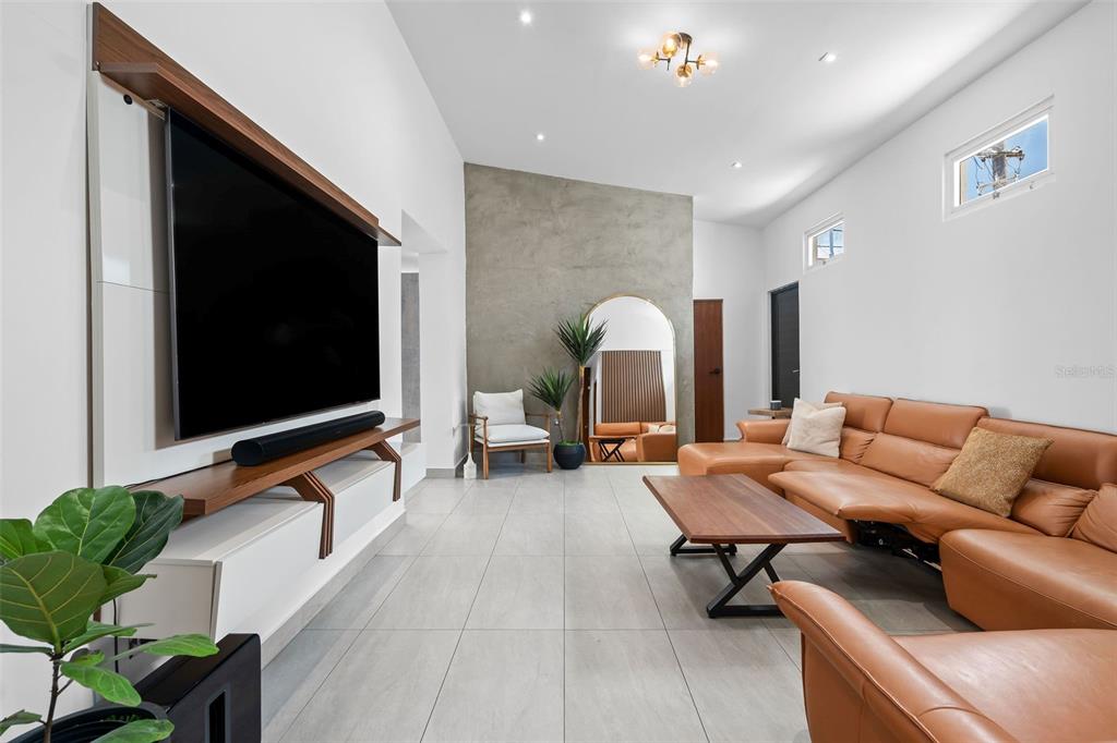 A modern living room features a large television, tan leather sectional, and concrete accent wall — JJ-12 CALLE ROSA DE LOS VIENTOS, DORADO, PR