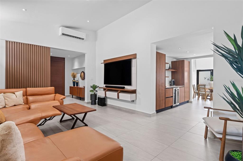 A modern living room features a tan leather sectional, wood accents, and an open kitchen — JJ-12 CALLE ROSA DE LOS VIENTOS, DORADO, PR