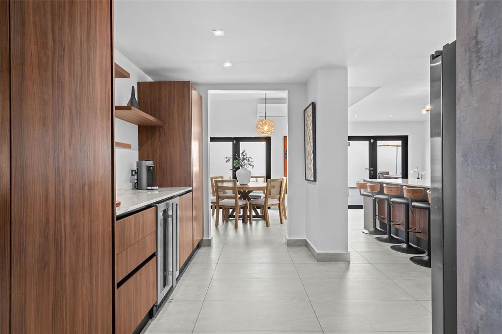 A modern kitchen features wood cabinetry, a wine cooler, and a view into a dining area — JJ-12 CALLE ROSA DE LOS VIENTOS, DORADO, PR