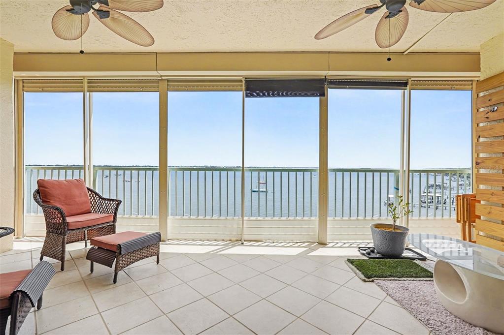 A screened-in balcony with tile flooring, wicker furniture, and a view of the water — 104 RIVERSIDE DRIVE UNIT 602, COCOA, FL