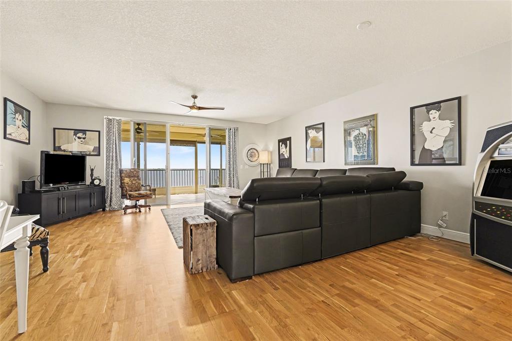 A living room features hardwood floors, a large sectional sofa, and a balcony with water views — 104 RIVERSIDE DRIVE UNIT 602, COCOA, FL