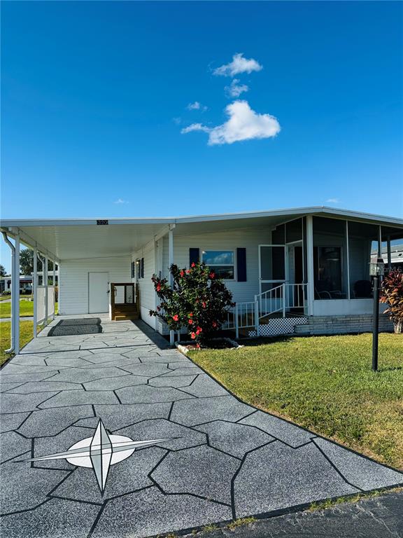 A manufactured home features a patterned concrete driveway with a compass rose design — 320 ALOHA DRIVE, HAINES CITY, FL