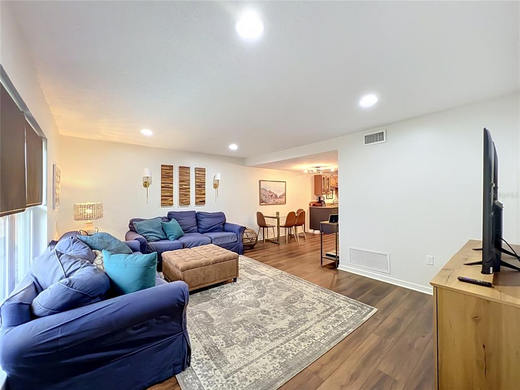 A living room with blue sofas, a patterned rug, and an open view to the kitchen — 603 WAVERLY LANE UNIT 405B, MAITLAND, FL