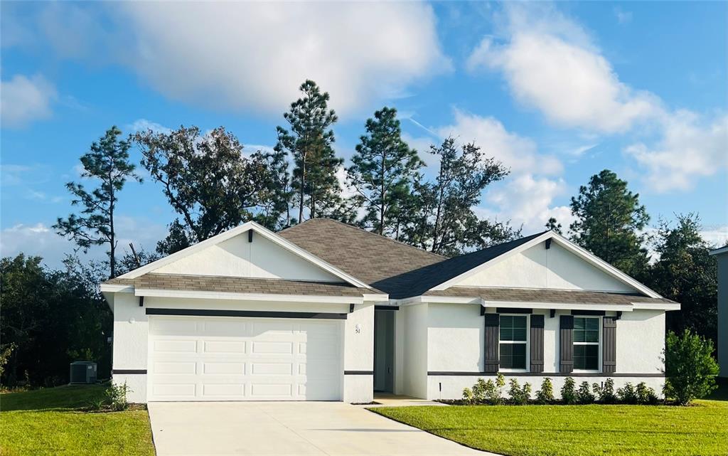 A single-story white house with a two-car garage and dark shutters under a cloudy sky — 51 HICKORY COURSE TRAIL, OCALA, FL