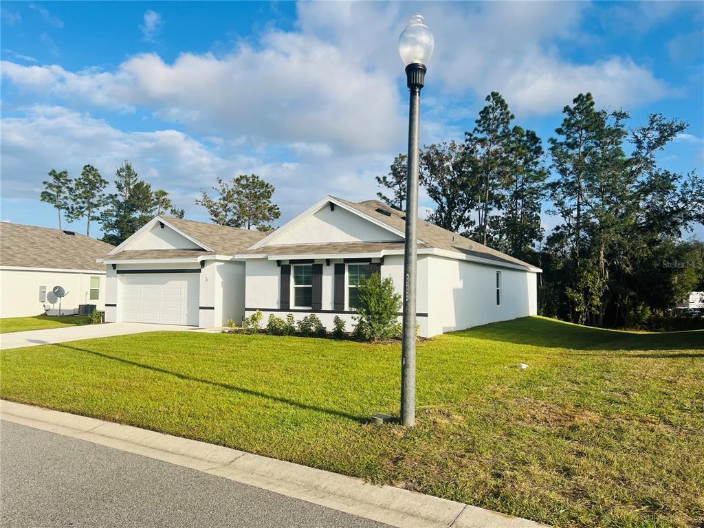 A single-story house with a white exterior, a two-car garage, and a front lawn — 51 HICKORY COURSE TRAIL, OCALA, FL