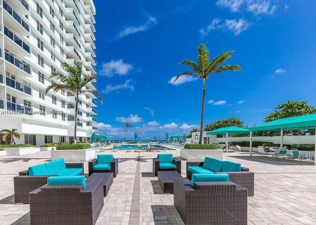 An outdoor patio features wicker lounge furniture with teal cushions overlooking a swimming pool — 3725 S Ocean Dr # 415, Hollywood FL 33019, HOLLYWOOD, FL