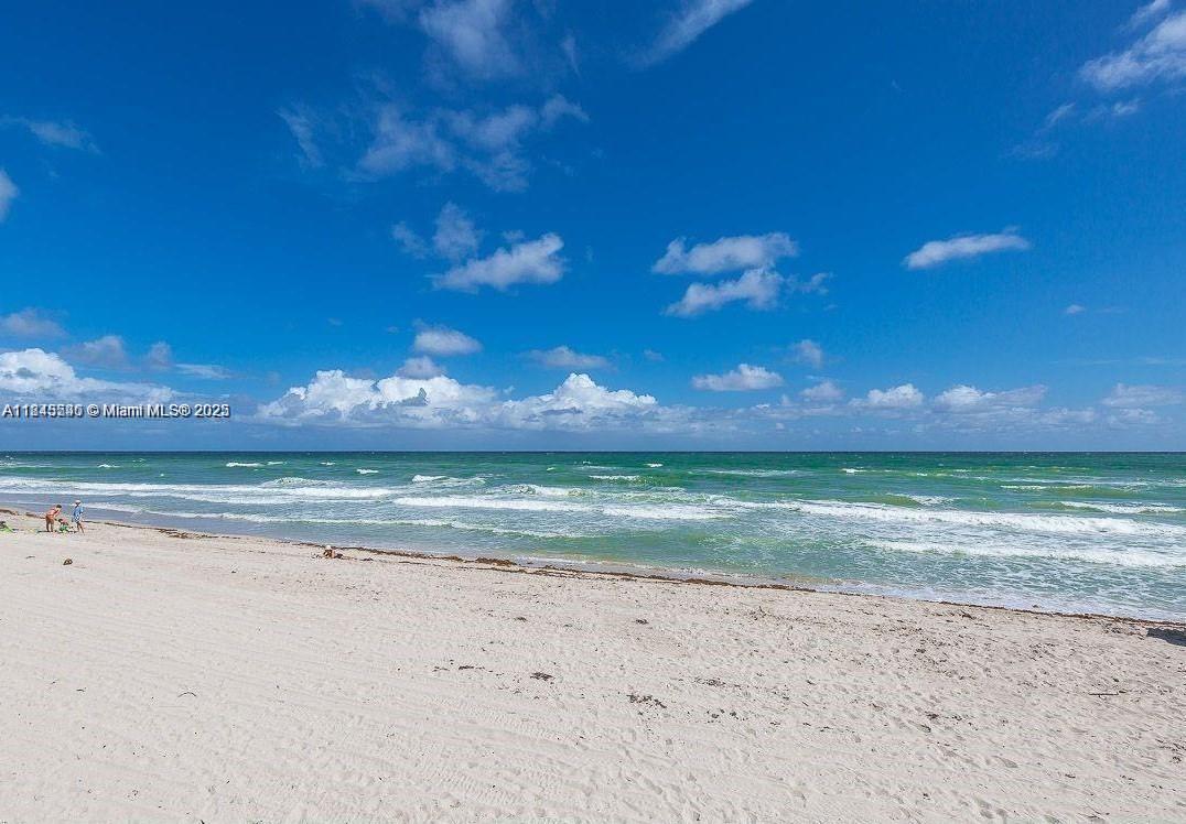 A sandy beach meets the ocean under a blue sky with scattered clouds — 3725 S Ocean Dr # 415, Hollywood FL 33019, HOLLYWOOD, FL