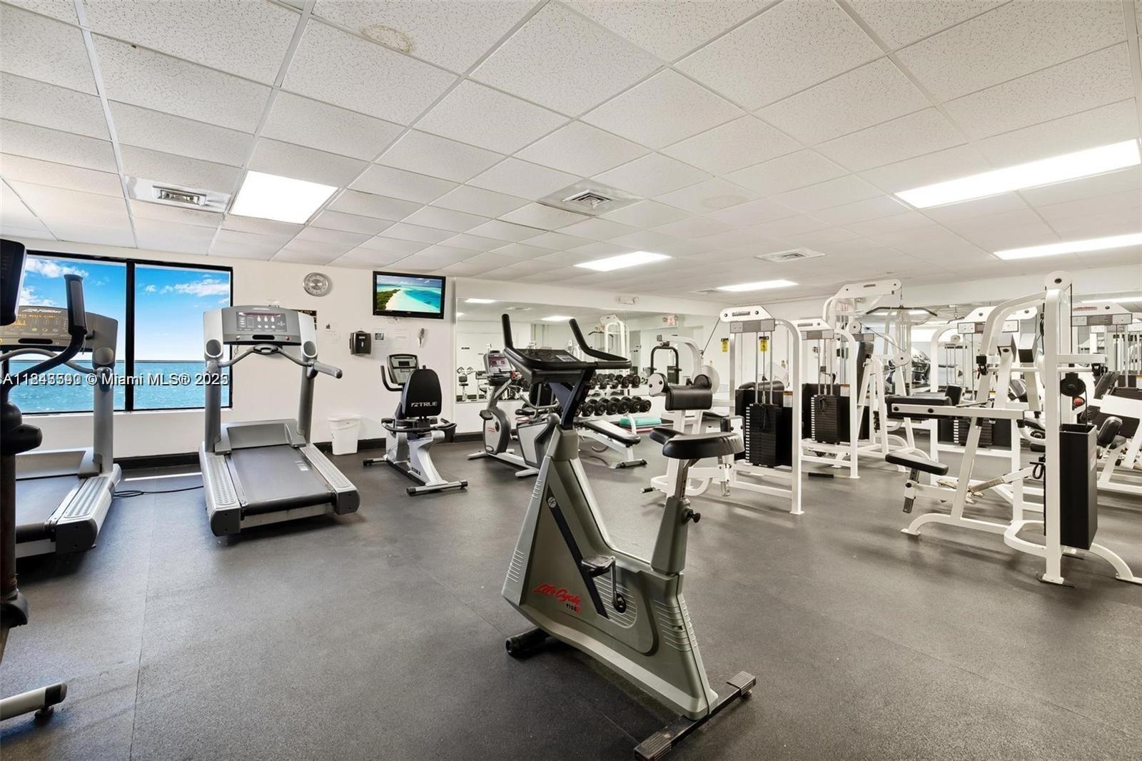 A gym with various exercise machines, rubber flooring, and a window overlooking the ocean — 3725 S Ocean Dr # 415, Hollywood FL 33019, HOLLYWOOD, FL