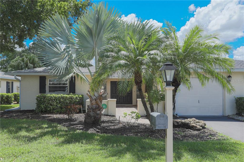 A single-story house with a white garage, a paved entryway, and several palm trees — 6986 W COUNTRY CLUB DRIVE N UNIT 6986, SARASOTA, FL