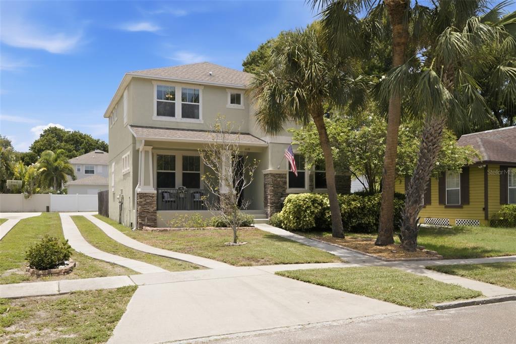 A two-story house with a covered front porch, stone accents, and a concrete driveway — 1110 10TH STREET N, ST PETERSBURG, FL