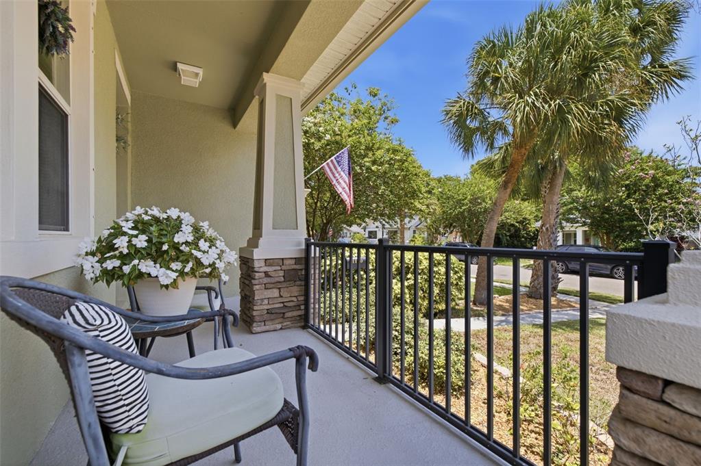A covered front porch features a stone-based pillar, black metal railing, and outdoor seating — 1110 10TH STREET N, ST PETERSBURG, FL