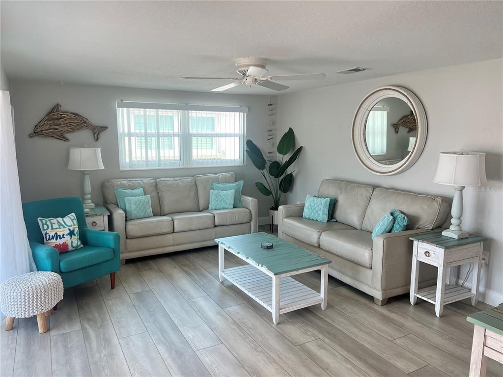 A living room features two light-colored sofas, a teal armchair, and a wooden coffee table — 6154 MIDNIGHT PASS ROAD UNIT D02, SARASOTA, FL