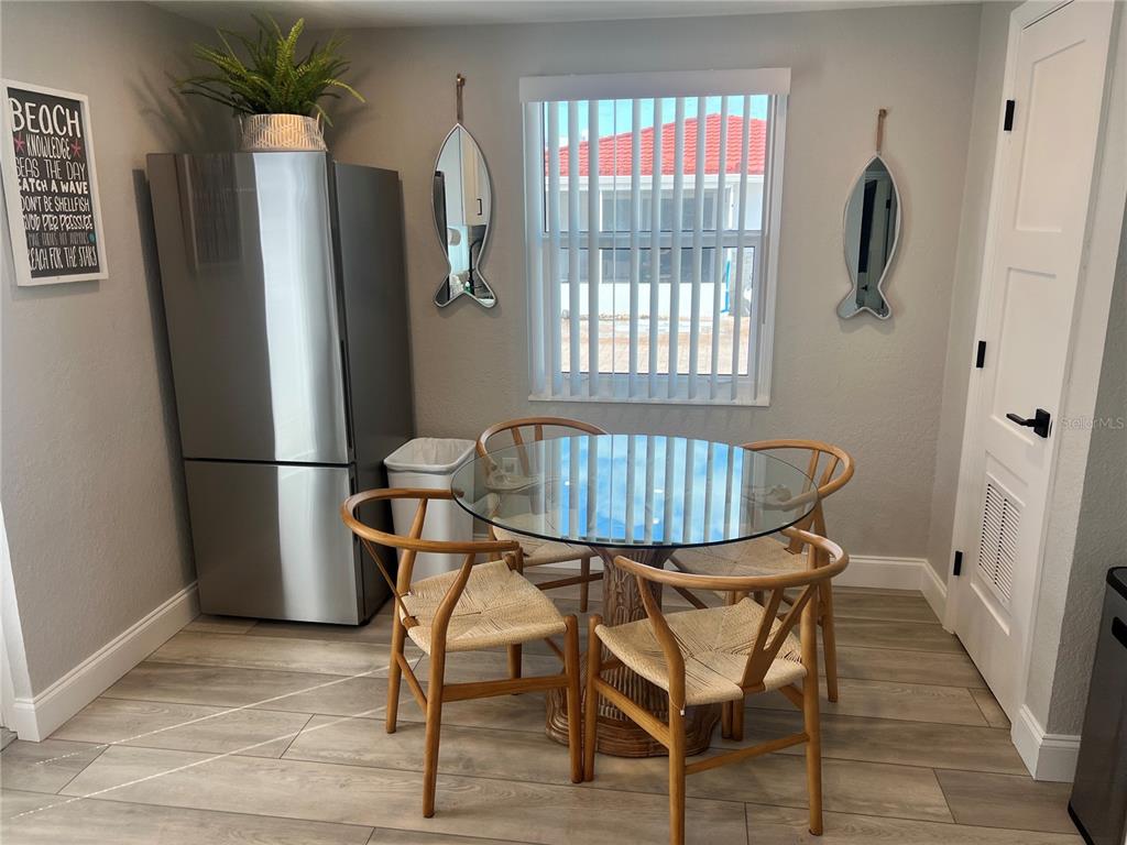 A dining area features a glass-topped table, four wooden chairs, a refrigerator, and fish-shaped mirrors — 6154 MIDNIGHT PASS ROAD UNIT D02, SARASOTA, FL