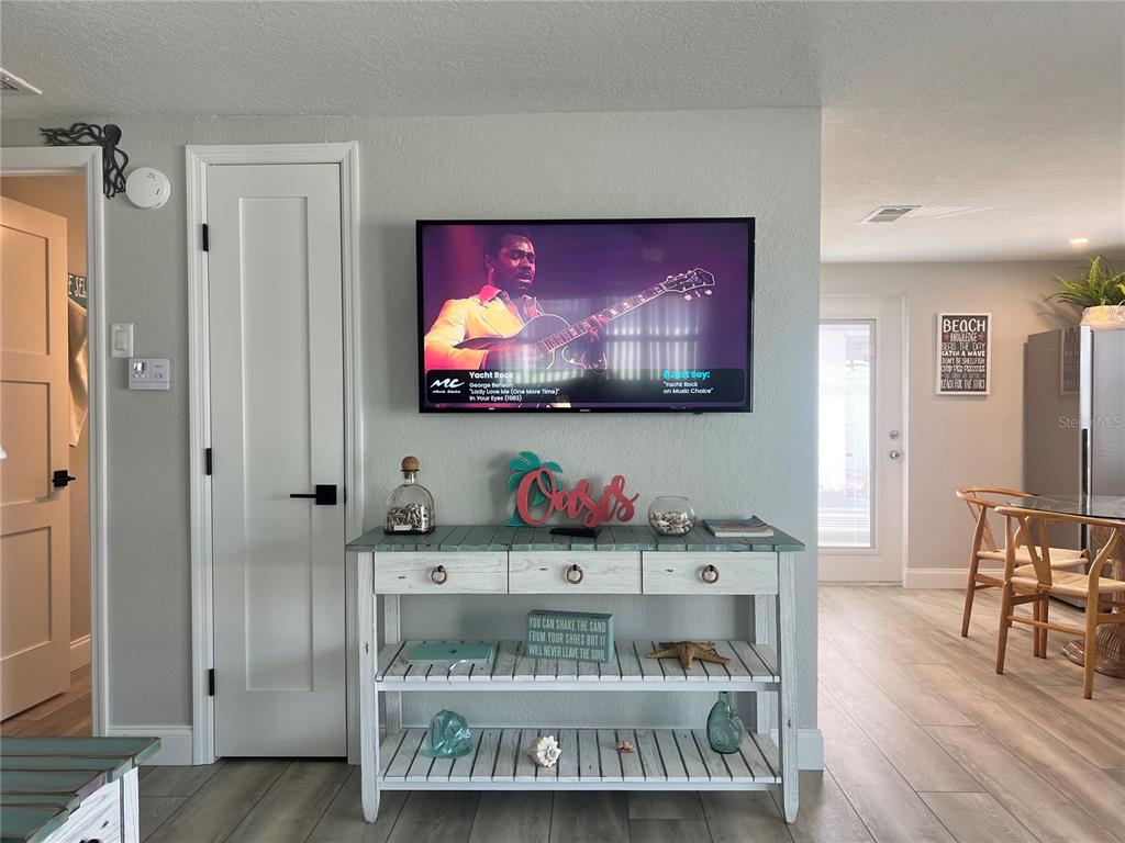 A living room features a wall-mounted television above a white wooden console table — 6154 MIDNIGHT PASS ROAD UNIT D02, SARASOTA, FL
