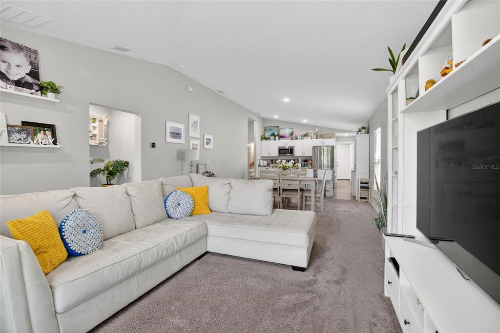 A living room features a white sectional sofa, gray carpeting, and an adjacent dining area — 13043 PENNYBROOK DRIVE, RIVERVIEW, FL