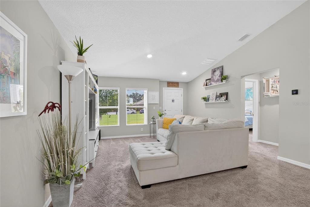 A living room features a white sectional sofa, a media console, and light gray walls — 13043 PENNYBROOK DRIVE, RIVERVIEW, FL