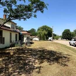 A two-story house with a wrap-around porch stands on a large, grassy lot — 202 S Jefferson Avenue, KS 67003, KS