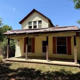 A side view of a light-colored house with a large, dry grassy yard — 202 S Jefferson Avenue, KS 67003, KS