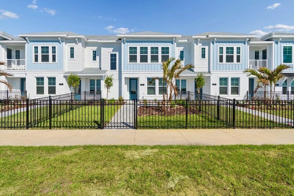 A row of two-story townhomes with blue and white siding, fenced yards, and a sidewalk — 7251 TIDELAND LANE, SARASOTA, FL