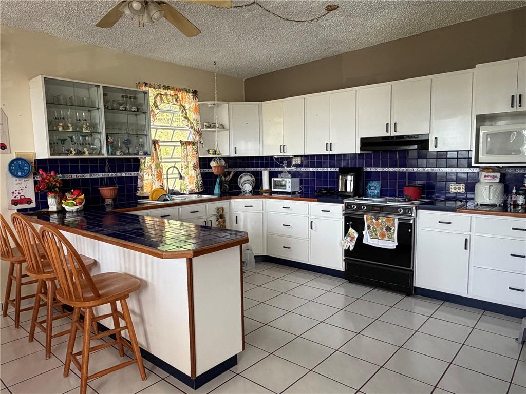A kitchen features white cabinets, blue tile countertops and backsplash, and white floor tiles — Sector Flor Sanchez BO. BUENA VISTA, BAYAMON, PR