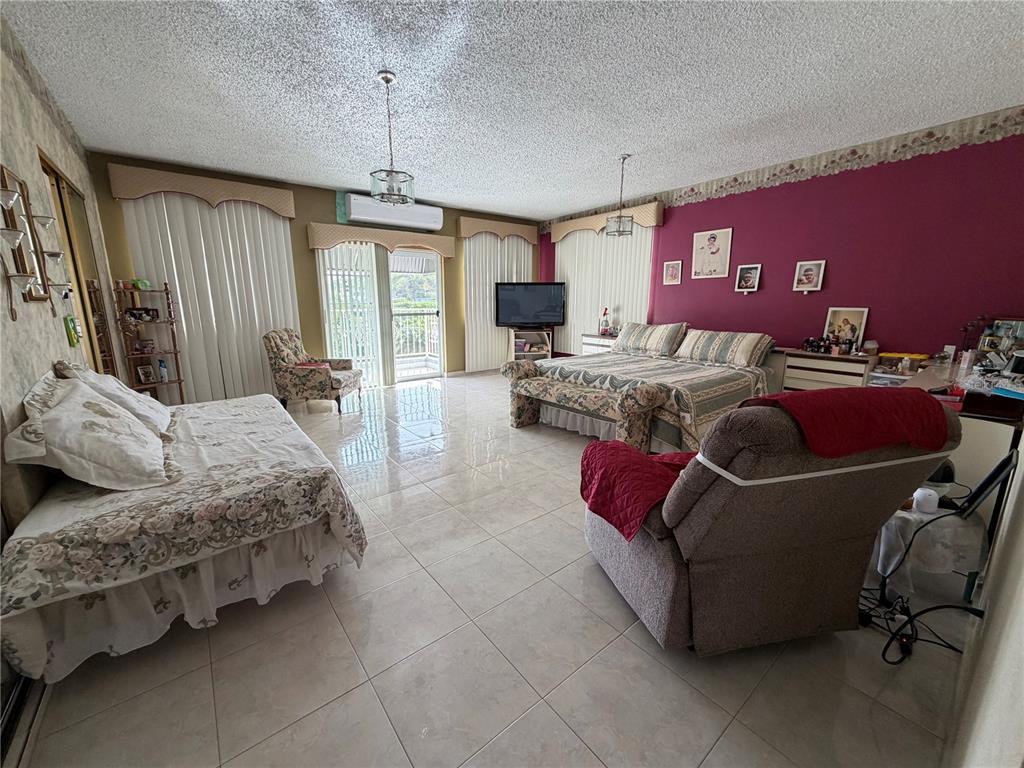 A spacious bedroom features tile flooring, a magenta accent wall, and two beds — Sector Flor Sanchez BO. BUENA VISTA, BAYAMON, PR