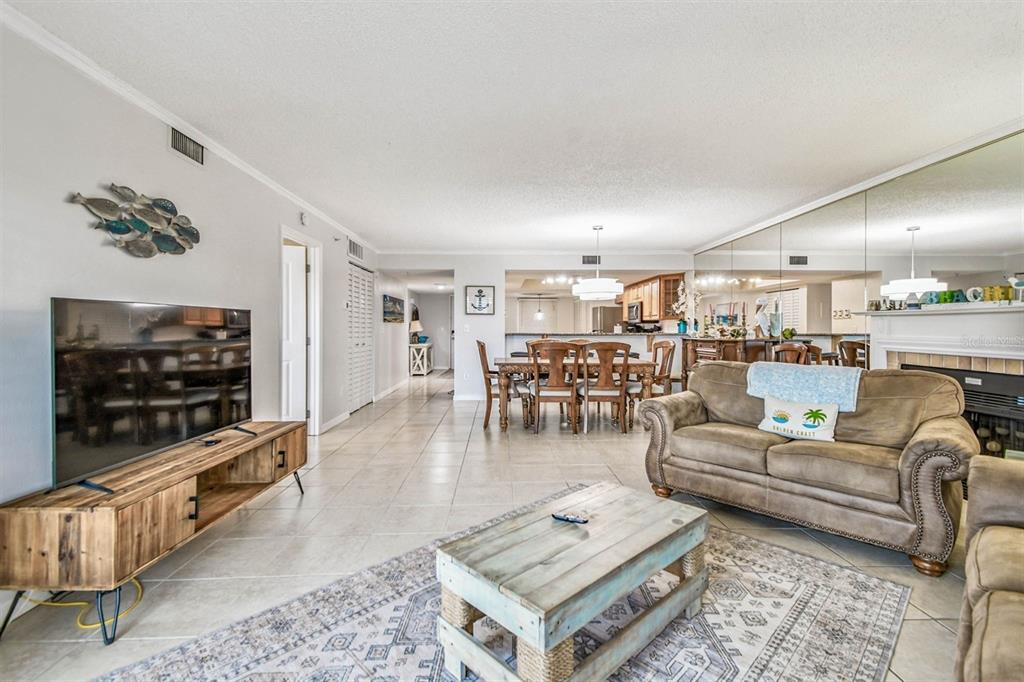 A living room with tile floors, a wooden media console, and a dining area beyond — 18400 GULF BOULEVARD UNIT 1301, INDIAN SHORES, FL