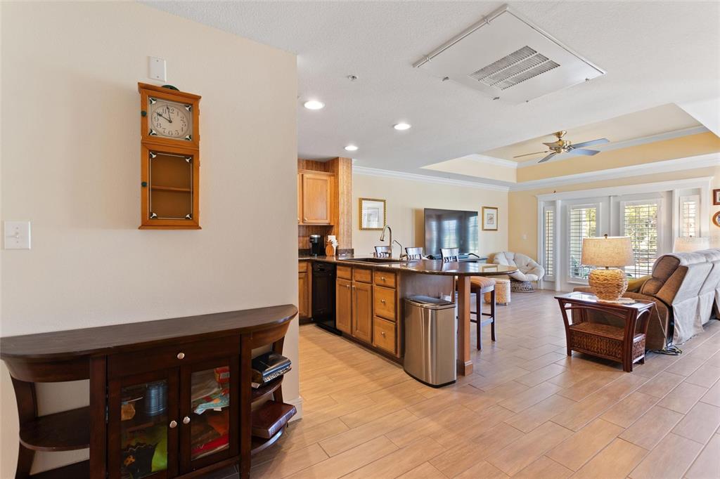 An open-concept kitchen and living area features wood cabinets, a kitchen island, and tile flooring — 1593 HERITAGE CROSSING COURT UNIT G, REUNION, FL