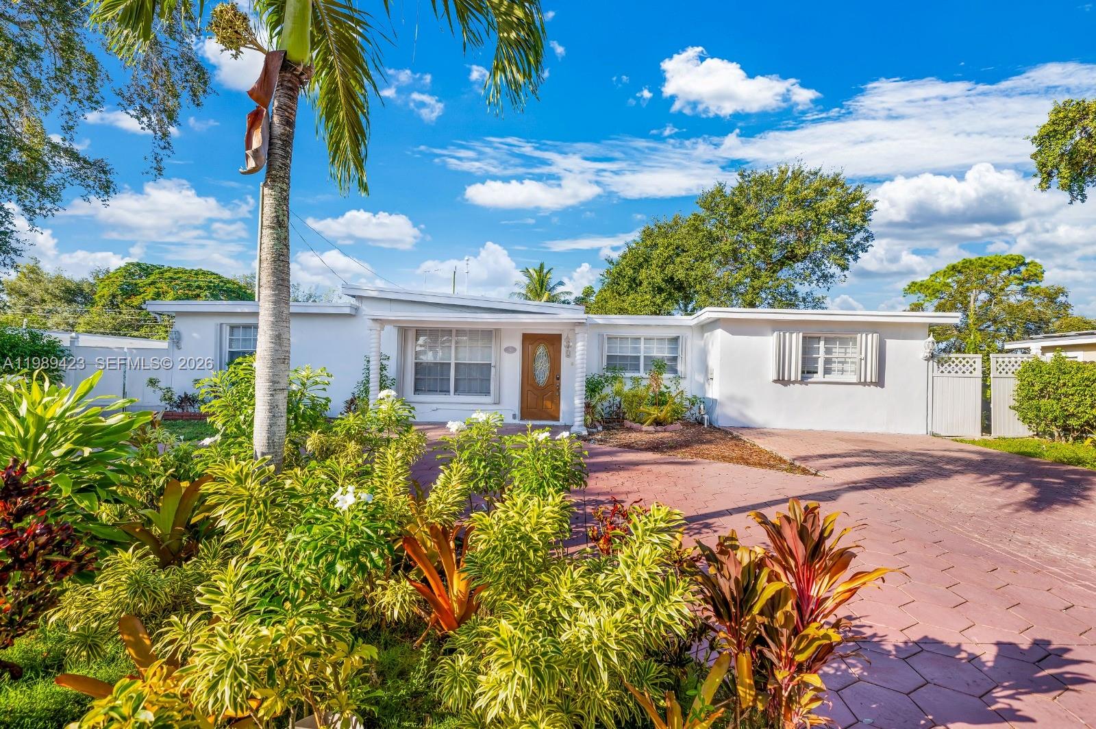 A single-story white house with a paved driveway and lush tropical landscaping in front — 38 Miami Gardens Rd, West Park FL 33023, WEST PARK, FL