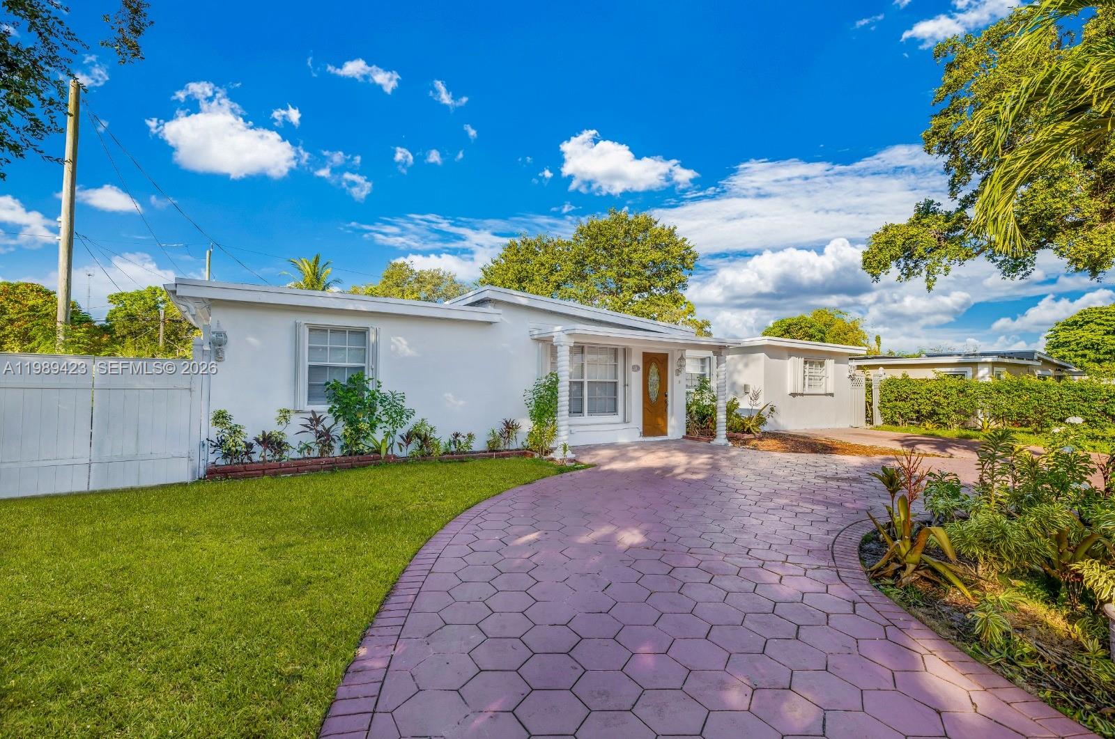 A white single-story house features a curved paved driveway and a green front lawn — 38 Miami Gardens Rd, West Park FL 33023, WEST PARK, FL