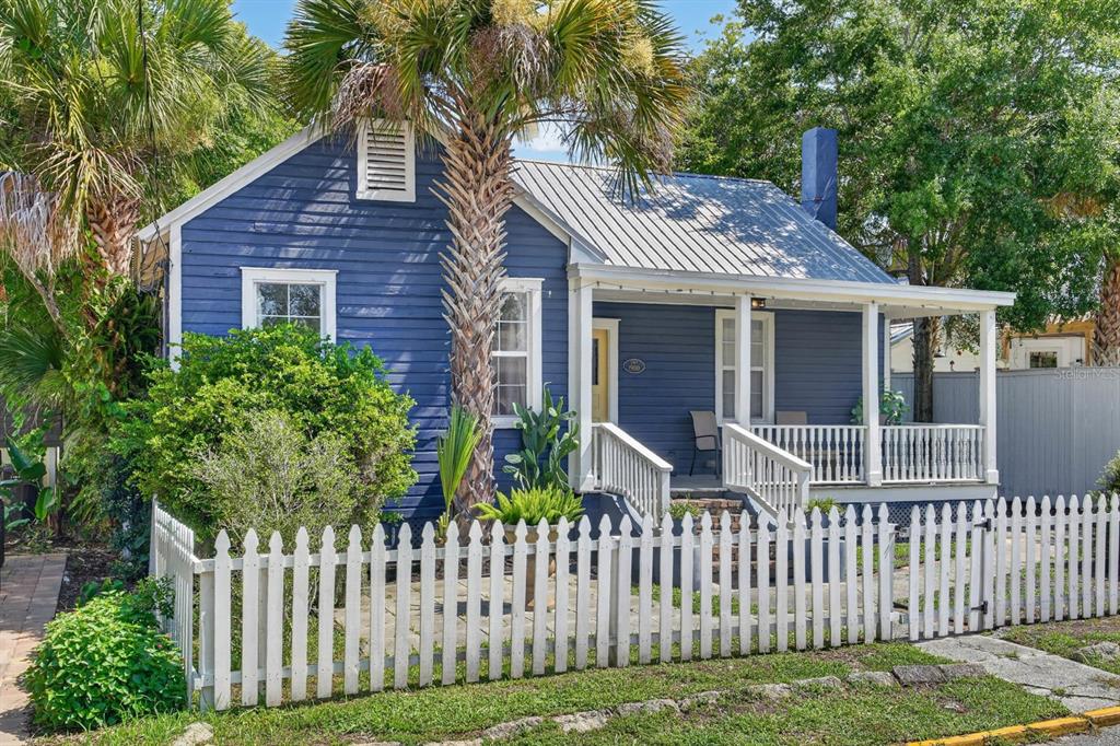 A blue cottage with a metal roof, front porch, and white picket fence — 28 JOINER STREET, ST AUGUSTINE, FL