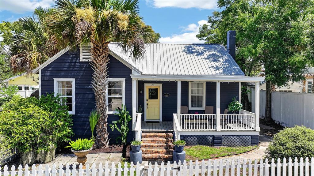 A blue cottage with a metal roof, a yellow front door, and a front porch — 28 JOINER STREET, ST AUGUSTINE, FL