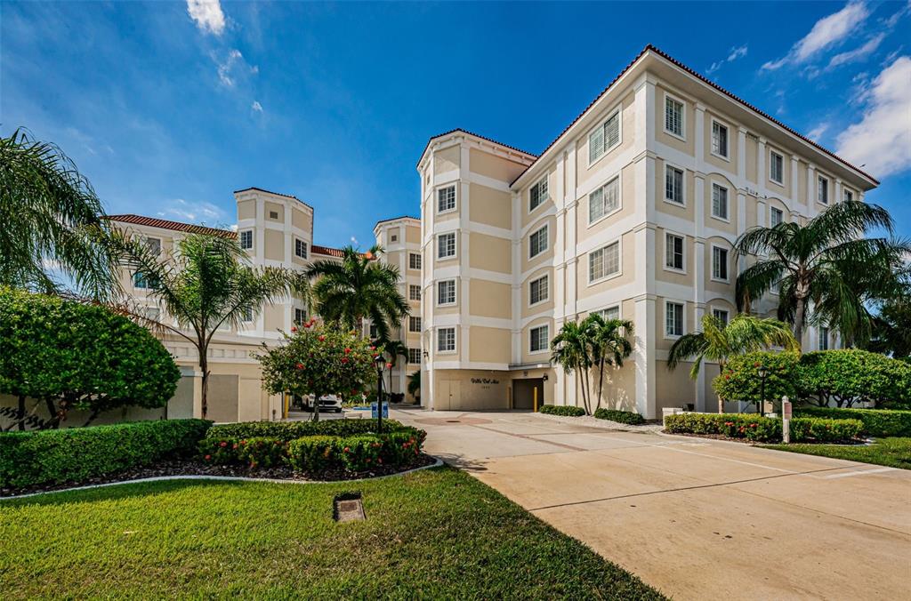 A multi-story beige apartment building with palm trees and a paved driveway in front — 1860 N FORT HARRISON AVENUE UNIT 103, CLEARWATER, FL
