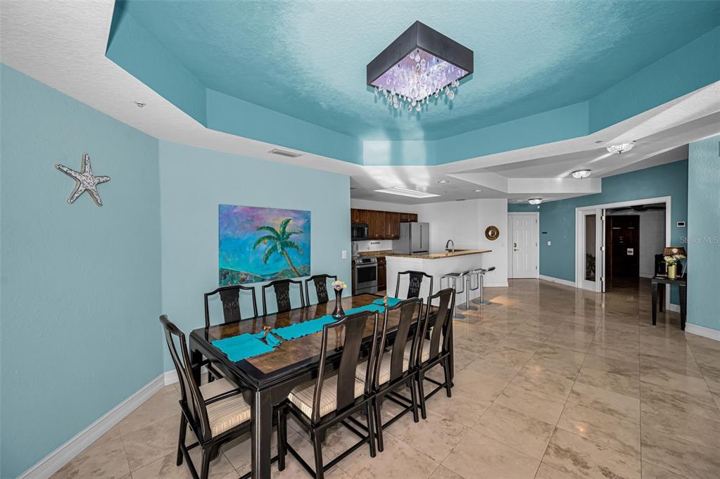 A dining area with a dark wood table and chairs sits before an open kitchen — 1860 N FORT HARRISON AVENUE UNIT 103, CLEARWATER, FL