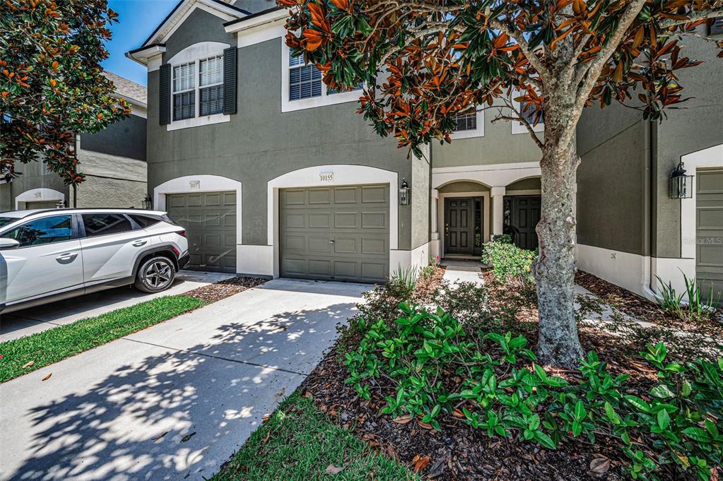 A two-story townhouse exterior features a two-car garage, a concrete driveway, and a front entrance — 10155 HAVERHILL RIDGE DRIVE, RIVERVIEW, FL