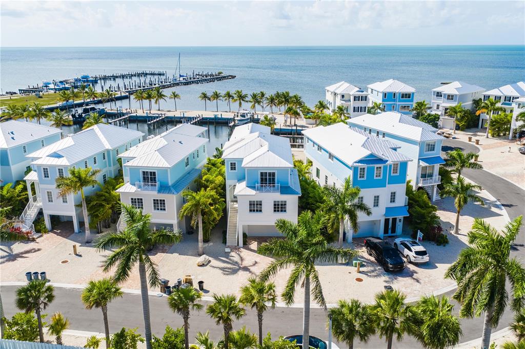 A covered balcony with wicker furniture overlooks a marina at sunset — 805 39TH STREET GULF, MARATHON, FL