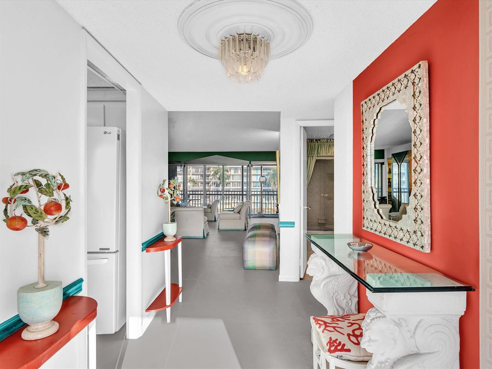 A hallway with a red accent wall, a glass console table, and a crystal chandelier — 1537 E Hillsboro Boulevard # 438, Deerfield Beach FL 33441, DEERFIELD BEACH, FL