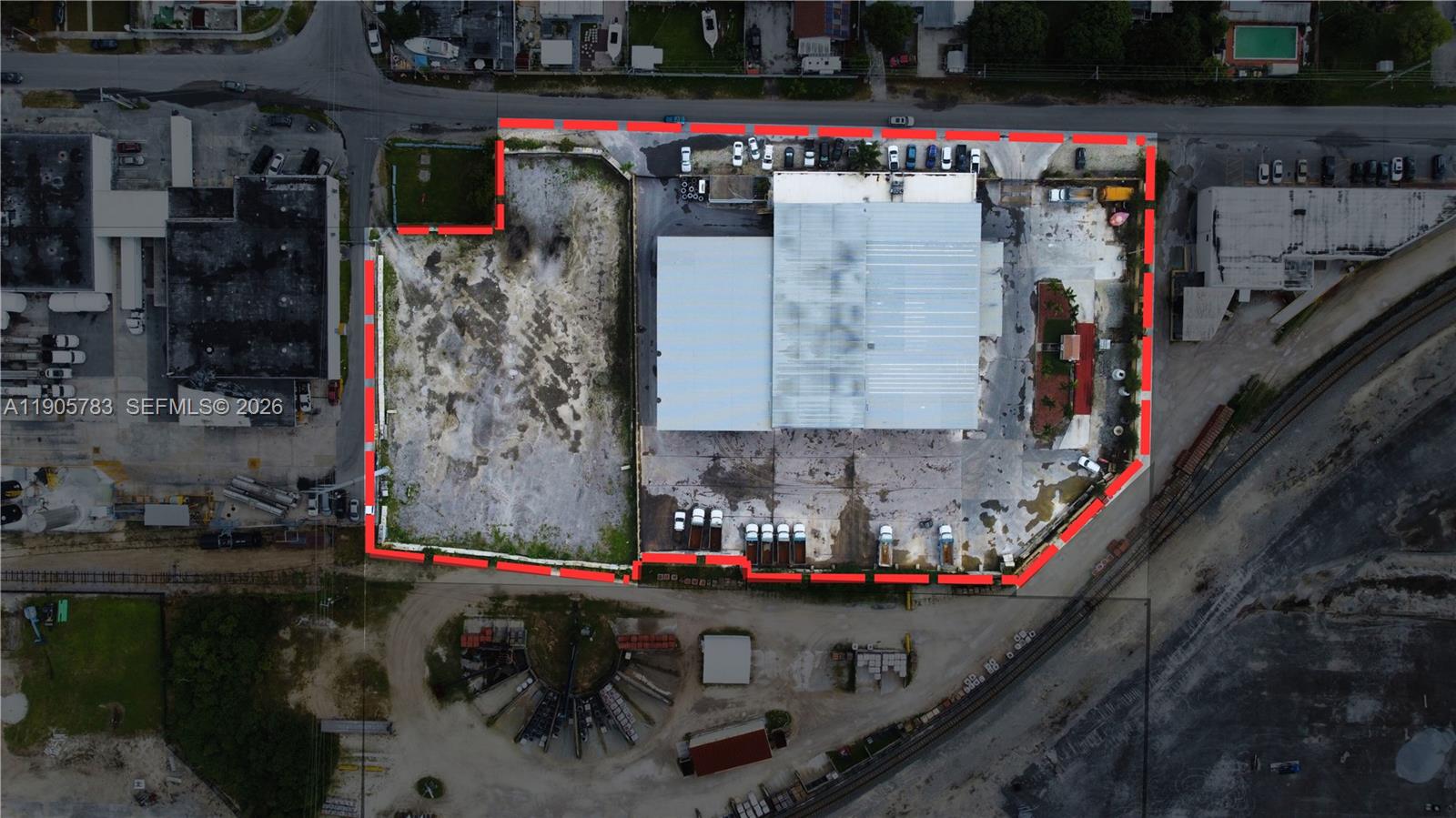 This aerial view shows a commercial property with a warehouse and a large paved lot — 8600 NW 36th Ave, Miami FL 33147, MIAMI, FL