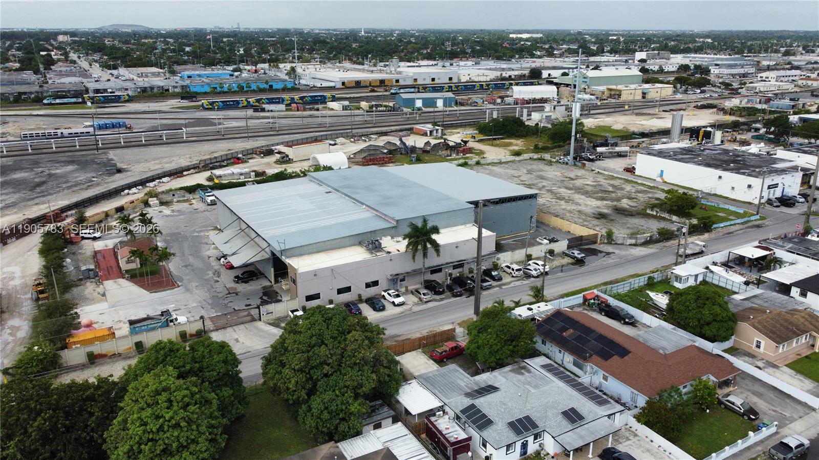 An aerial view shows a large industrial warehouse building surrounded by parking and railroad tracks — 8600 NW 36th Ave, Miami FL 33147, MIAMI, FL