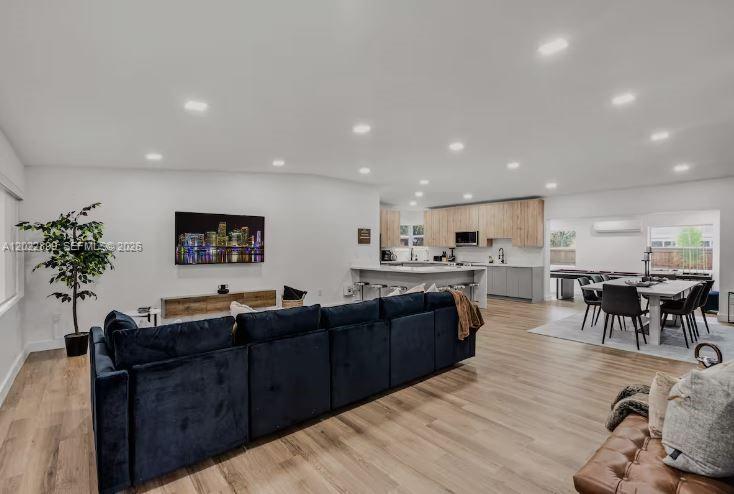 An open-concept living room features a large dark blue sectional sofa and a modern kitchen — 17621 NE 7th Ave, Miami FL 33162, MIAMI, FL