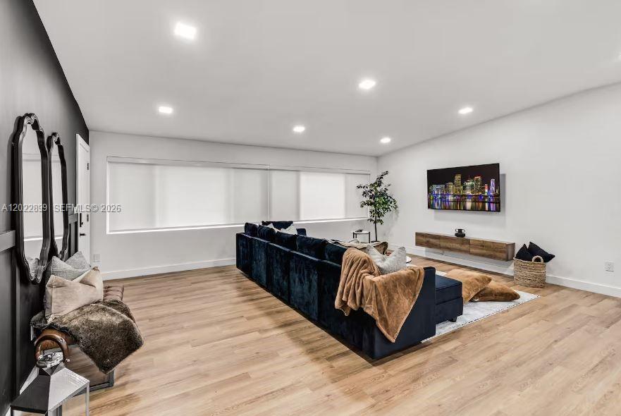 A living room features a large blue sectional sofa, wood flooring, and a wall-mounted television — 17621 NE 7th Ave, Miami FL 33162, MIAMI, FL