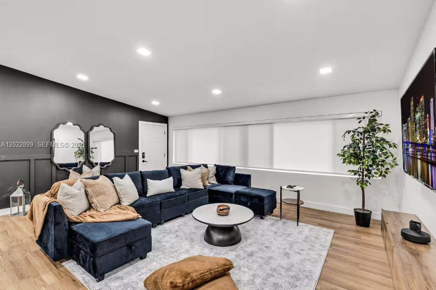 A living room features a dark blue sectional sofa, a round coffee table, and wall mirrors — 17621 NE 7th Ave, Miami FL 33162, MIAMI, FL