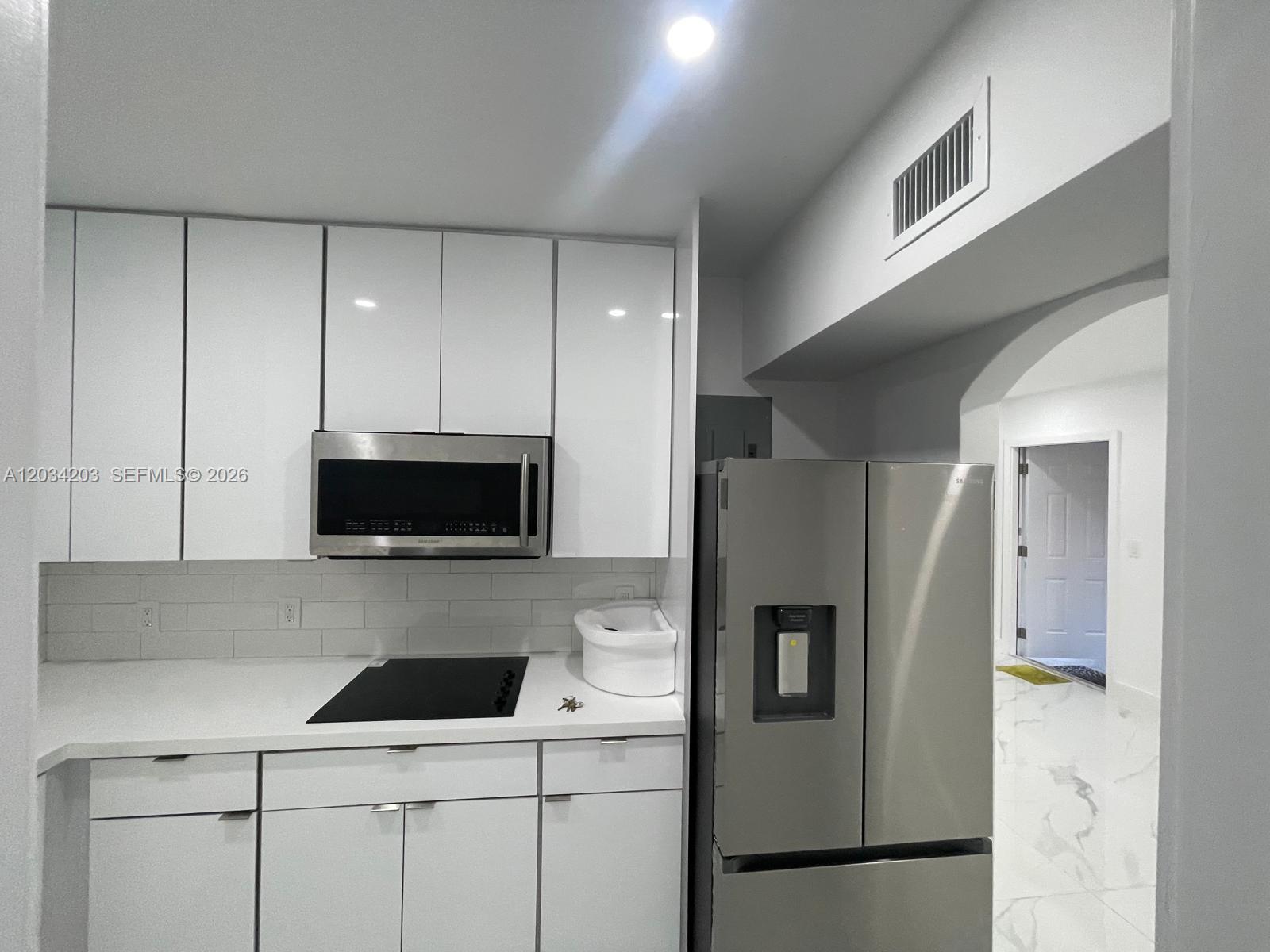 A modern kitchen features white cabinets, stainless steel appliances, and white subway tile backsplash — 2103 SW 60th Ave # 2, Miami FL 33155, MIAMI, FL