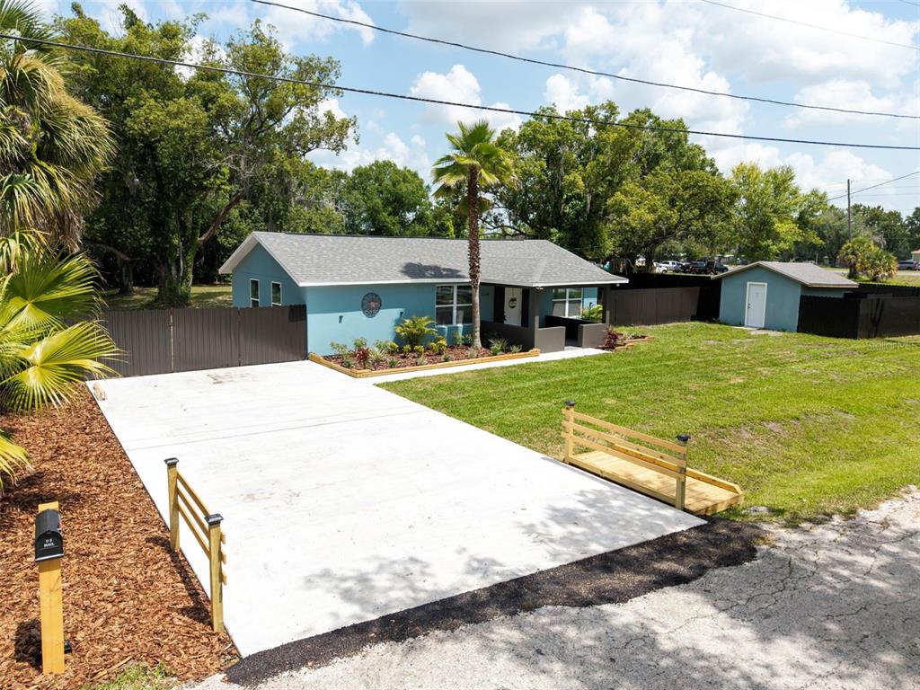 A blue house with a gray roof features a concrete driveway and a wooden bridge — 21149 LITTLE LAKE THOMAS ROAD, LAND O LAKES, FL