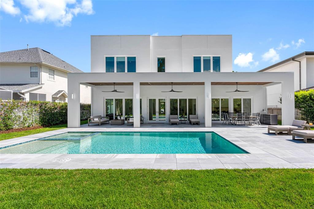 A modern white two-story house features a covered patio, swimming pool, and landscaped backyard — 3208 W LAWN AVENUE, TAMPA, FL