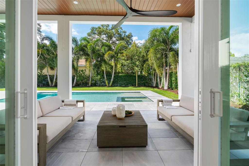 A covered outdoor patio features two sofas, a coffee table, and a swimming pool view — 3208 W LAWN AVENUE, TAMPA, FL