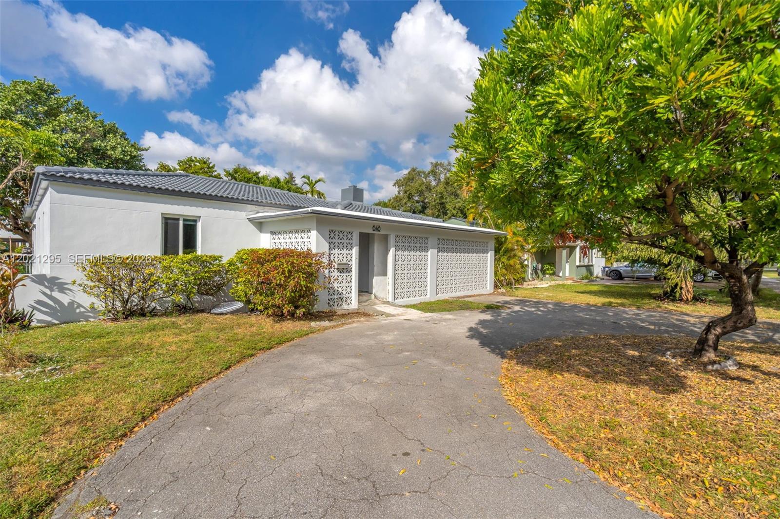 A white single-story house features a decorative breeze block facade and a curved asphalt driveway — 648 South Dr, Miami Springs FL 33166, MIAMI SPRINGS, FL