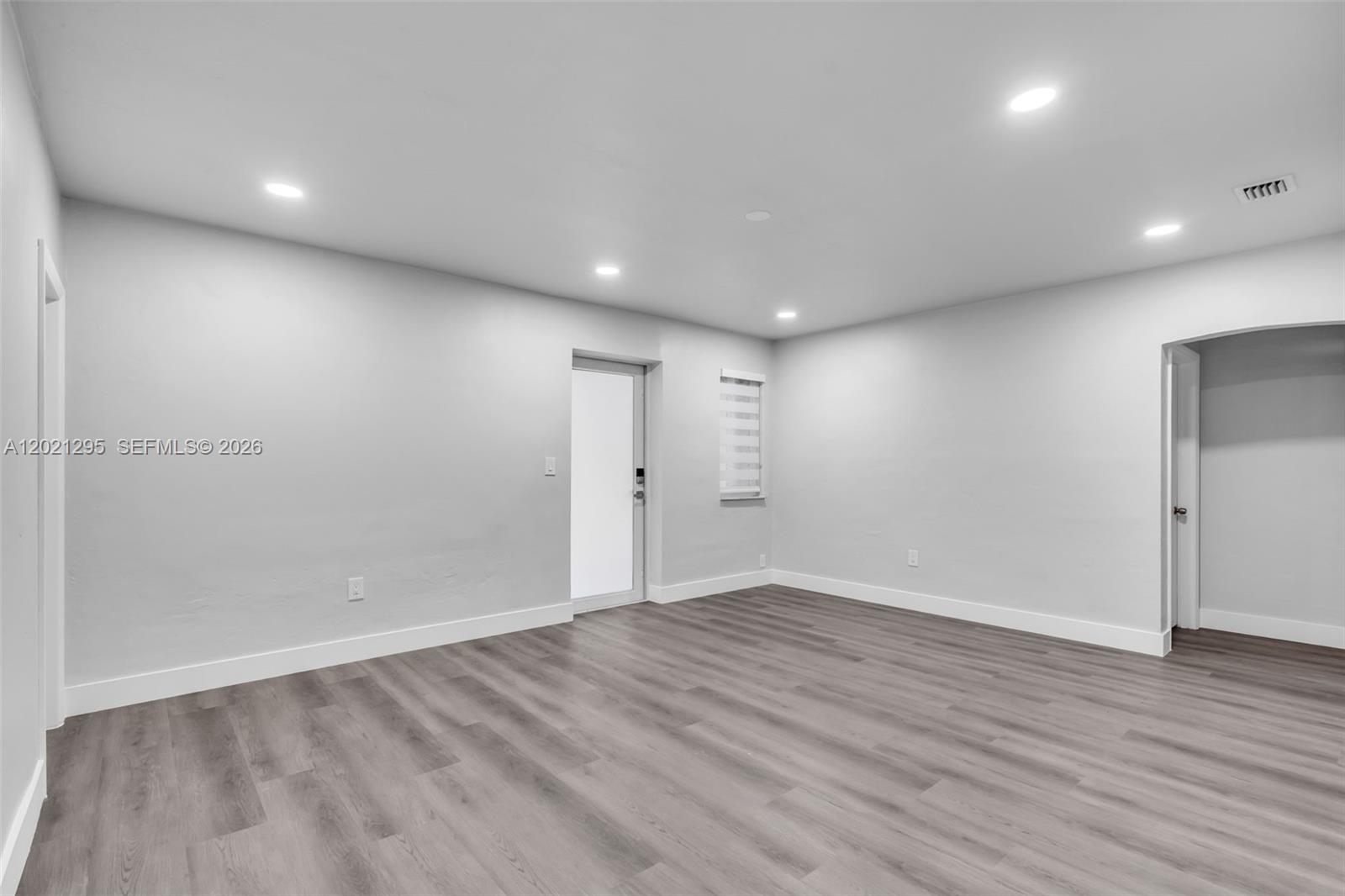 An empty room features light gray walls, recessed lighting, and wood-look vinyl plank flooring — 648 South Dr, Miami Springs FL 33166, MIAMI SPRINGS, FL
