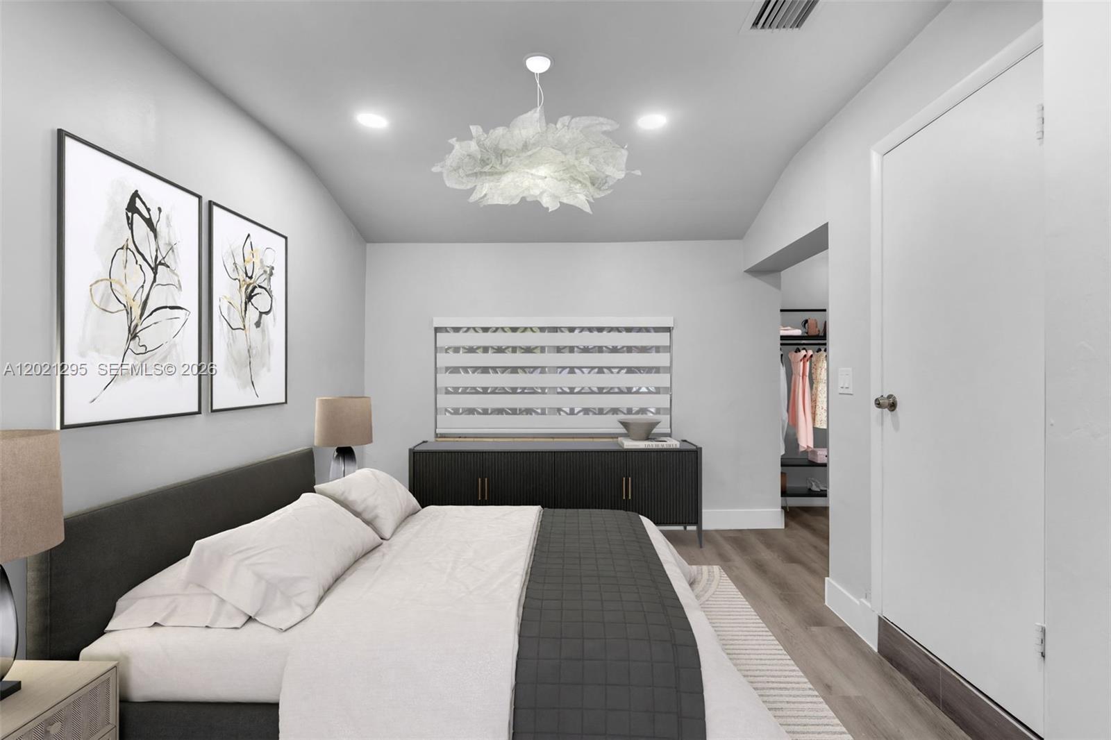 This bedroom features a dark bed frame, a modern chandelier, and a walk-in closet — 648 South Dr, Miami Springs FL 33166, MIAMI SPRINGS, FL