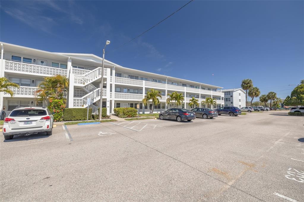 A multi-story apartment building with exterior staircases and a parking lot in the foreground — 1001 77TH AVENUE N UNIT 112, ST PETERSBURG, FL