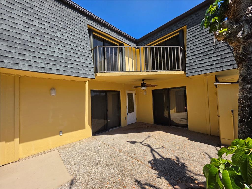 A two-story building exterior features a yellow stucco wall, a concrete patio, and a balcony — 3824 SAXON DRIVE, NEW SMYRNA BEACH, FL